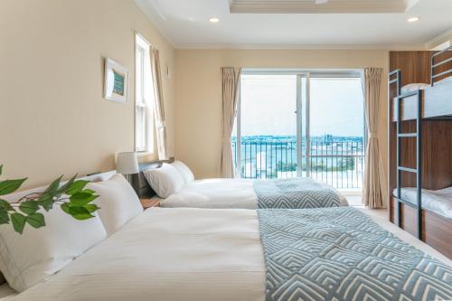 two beds in a hotel room with a large window at  M’sOceanⅡ Uruma in Uruma
