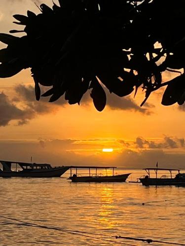 two boats in the water with a sunset in the background at Coco Divers & Homestay Bunaken in Manado