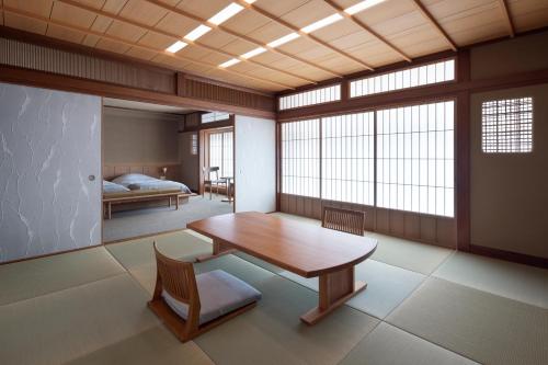 a room with a table and a bed and windows at Mikuniya in Toyooka