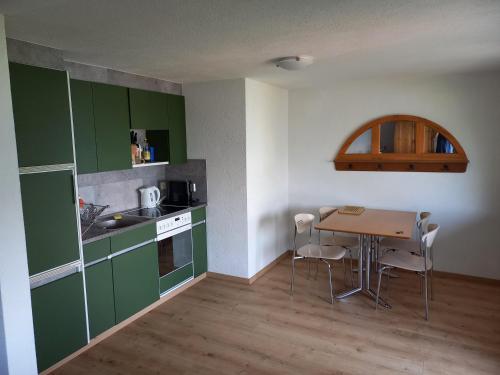 eine Küche mit grünen Schränken und einem Tisch mit Stühlen in der Unterkunft Seeblick in Aeschlen