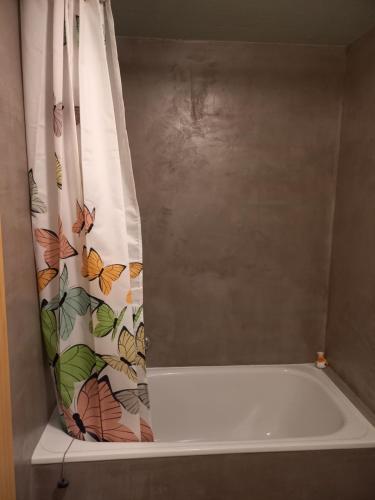 a bath tub with a shower curtain with butterflies on it at Seeblick in Aeschlen
