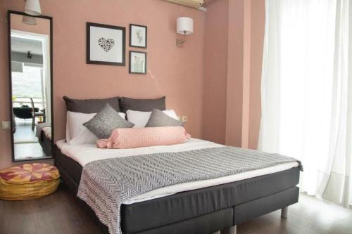 a bedroom with a bed with pink walls and a mirror at Port View Suite, Kavala in Kavala