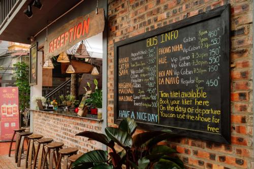 un mur en briques avec un menu et quelques tabourets dans l'établissement Wafami Hostel Ninh Binh, à Ninh Binh