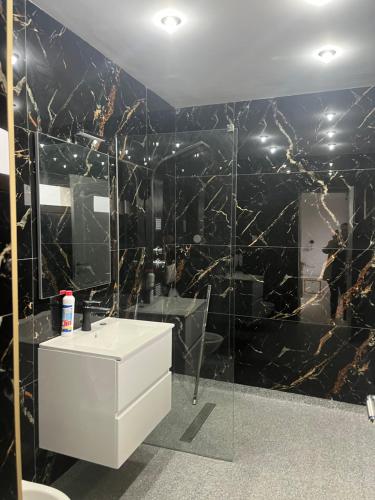 ein Bad mit einer schwarzen und goldenen Marmorwand in der Unterkunft Casa duplex in Alba Iulia