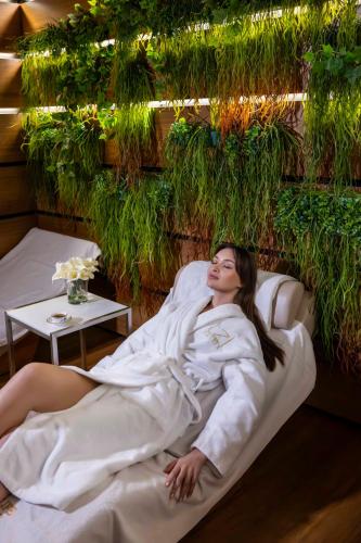 a woman in a robe laying on a bed at Tzl Suites Hotel Nişantaşı in Istanbul