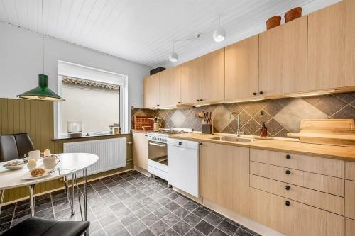 a kitchen with wooden cabinets and a table in it at Nyd den skønne natur ved hav og fjord in Thyborøn