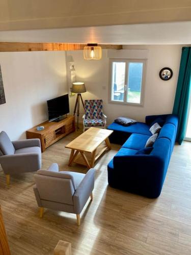 un salon avec un canapé bleu et des chaises dans l'établissement Rive gauche (bord de mer), à Réville