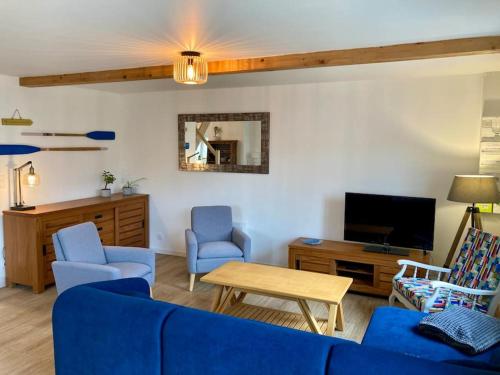 een woonkamer met een blauwe bank en een tv bij Rive gauche (bord de mer) in Réville
