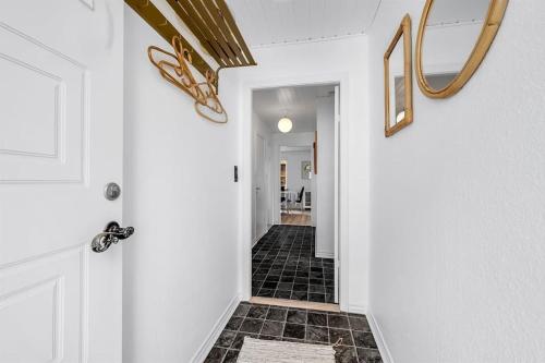a hallway with a white door and a black tile floor at Nyd den skønne natur ved hav og fjord in Thyborøn