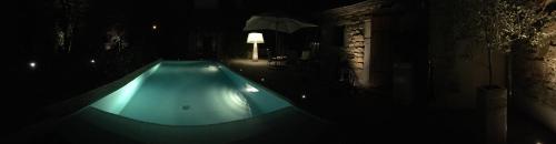an empty swimming pool at night with an umbrella at Maison coup de cœur in Fauverney