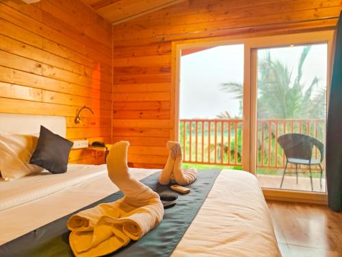 une personne dormant sur un lit dans une chambre avec fenêtre dans l'établissement The Lazy Cabanas, à Candolim