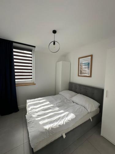 a bedroom with a bed with white sheets and a window at Domy przy Spokojnej in Jantar