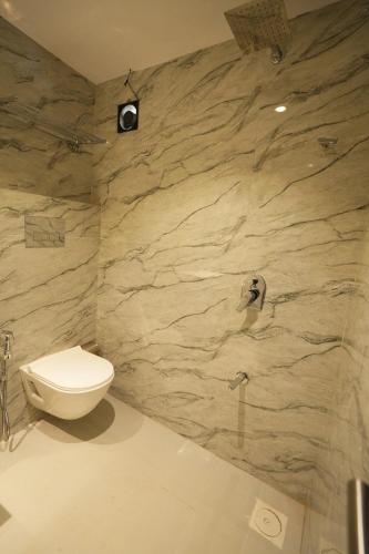 a bathroom with a toilet and a stone wall at HOTEL BOSTON in Mumbai