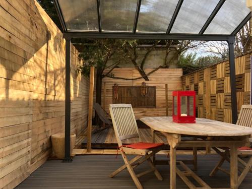 einen Holztisch und Stühle auf einer Terrasse mit Glasdach in der Unterkunft Romantic Room - Superbe Appartement Studio Jardin - Proche Disneyland Paris in Crécy-la-Chapelle