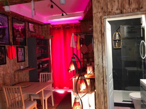 une salle à manger avec une table et un éclairage rose dans l'établissement Romantic Room - Superbe Appartement Studio Jardin - Proche Disneyland Paris, à Crécy-la-Chapelle
