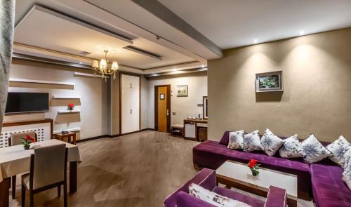 a living room with a purple couch and a tv at Manor Luxury Hotel Baku in Baku