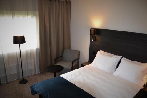 a hotel room with a bed and a chair at Best Western Hotel Scheele in Köping