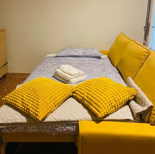 Una cama amarilla con dos almohadas encima. en Sun&Sea Apartment en Lido di Ostia