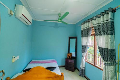 1 dormitorio con paredes azules, 1 cama y ventana en Passi CK Homestay, en Pasikuda