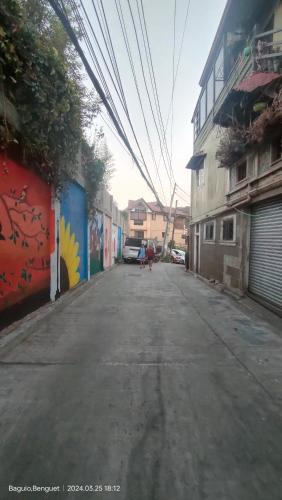 an empty street in an alley with buildings and power lines at Kochimoto Guesthouse in Baguio