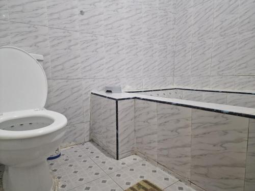 een badkamer met een toilet en een betegelde muur bij Blueberry suite 1 in Accra