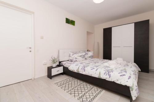 a white bedroom with a bed and a rug at Casa cu Lavanda in Sinaia