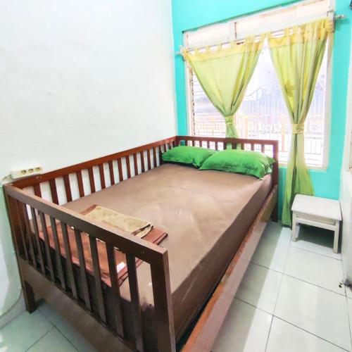 uma cama de madeira num quarto com uma janela em Rumah Teman Homestay em Semarang