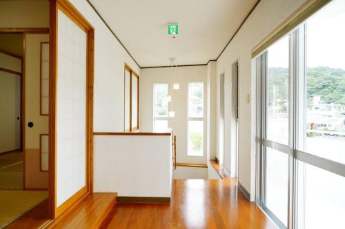 an empty hallway with large windows and wooden floors at 【駐車場4台！】都会の喧騒から離れ大自然に囲まれた豪邸～大石林山への観光にも最適～ in Kunigami