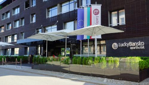 a hotel with umbrellas in front of a building at Lucky Bansko Aparthotel SPA & Relax in Bansko