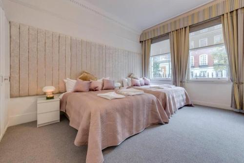 ein großes Schlafzimmer mit 2 Betten und einem Fenster in der Unterkunft Harley Street Spectacular Suites with High Ceilings, High Luxury in London
