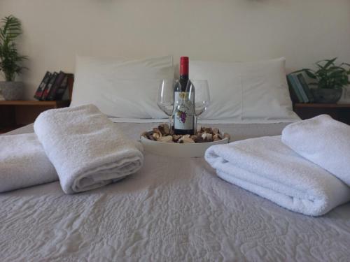 Una cama con toallas y una botella de vino y copas de vino. en Happy Days, en Agia Galini