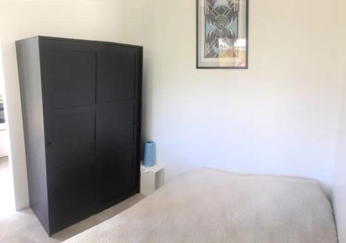 a bedroom with a black cabinet with a blue candle at Studio avec jardin à 2km de L'Océan ! in Labenne