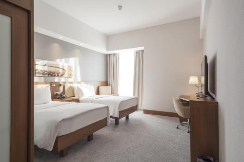 a hotel room with two beds and a desk at Hampton By Hilton Kocaeli Symbol in Kocaeli