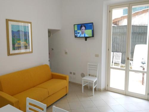 a living room with a couch and a tv on a wall at Grottammare mon amour Lori, con cortile privato in Grottammare