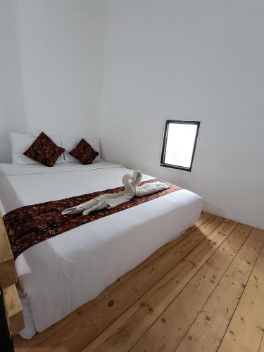 a bedroom with a bed with white sheets and a mirror at Jogja Amor Hotel in Demangan
