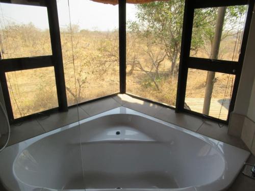 een groot bad in een kamer met een raam bij Elephants' Cottage - 102 Mjejane Game Reserve, KNP in Hectorspruit