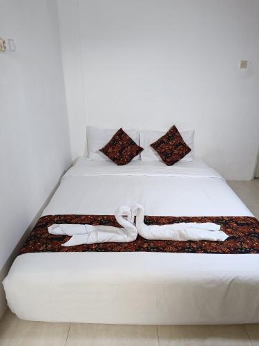 Una cama blanca con dos toallas blancas. en Jogja Amor Hotel, en Demangan