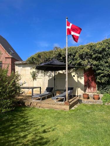 a flag and two chairs under an umbrella at Nyd den skønne natur ved hav og fjord in Thyborøn