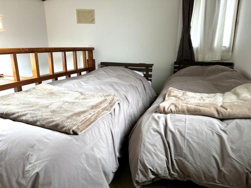 dwa łóżka siedzące obok siebie w pokoju w obiekcie Nozawaonsen Guest House Miyazawa w mieście Nozawa Onsen