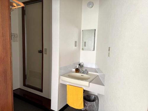 a bathroom with a white sink and a yellow chair at Nozawaonsen Guest House Miyazawa in Nozawa Onsen