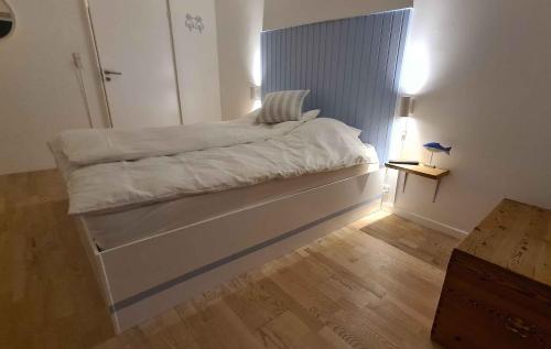 ein weißes Bett in einem Zimmer mit Holzboden in der Unterkunft Sunset Lodge With View Over Grnsund in Stubbekøbing