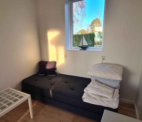Zimmer mit einem Bett mit Fenster und einem Segelboot. in der Unterkunft Sunset Lodge With View Over Grnsund in Stubbekøbing
