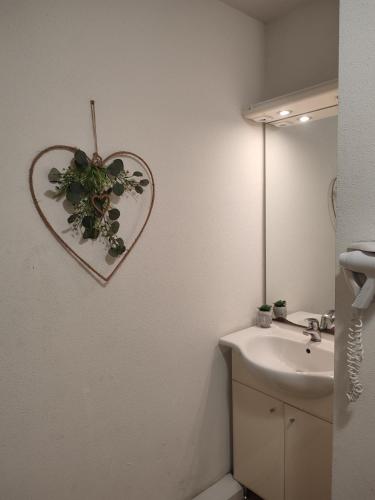 La salle de bains est pourvue d'un miroir en forme de cœur et d'un lavabo. dans l'établissement Ma Pause Normande T3 Les Isles de Sola, à Grandcamp-Maisy