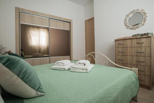 a bedroom with a green bed with towels on it at Pearl of Stegna - Beach House in Archangelos