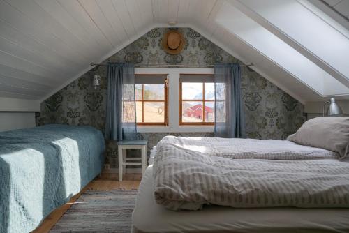 um quarto no sótão com 2 camas e uma janela em Klara House em Isfjorden