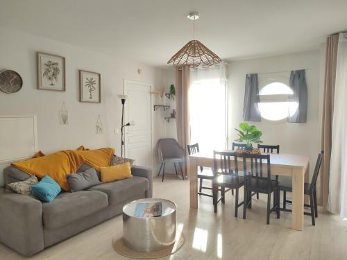 un salon avec un canapé et une table dans l'établissement Ma Pause Normande T3 Les Isles de Sola, à Grandcamp-Maisy