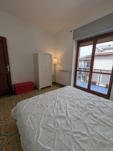 un grande letto bianco in una stanza con finestra di Intero appartamento nel cuore di Maiori a Maiori