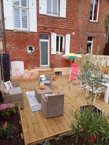 - une terrasse avec des canapés et des chaises devant un bâtiment en briques dans l'établissement Maison de vacances familiale à Trouville-sur-mer, à Trouville-sur-Mer