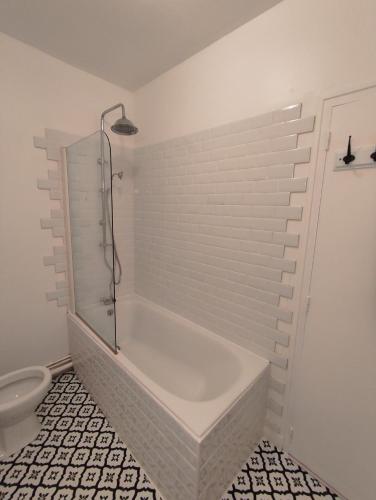 La salle de bains blanche est pourvue d'une baignoire et de toilettes. dans l'établissement Les Genêts d'Or, à Saint-Jean-le-Thomas