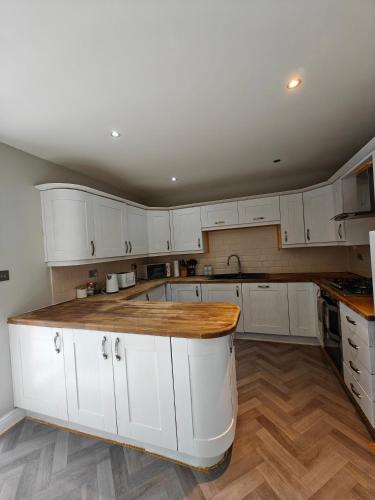 a kitchen with white cabinets and a wooden counter top at Under 10 Mins to NEC BHX - Walk to JLR -2 Large Living Areas - 4 Bedroom Spacious Home - Van Parking x2 - 5 Beds Excellent Equipped Home - NR A45 Solihull Bypass M42 HS2 Works in Solihull
